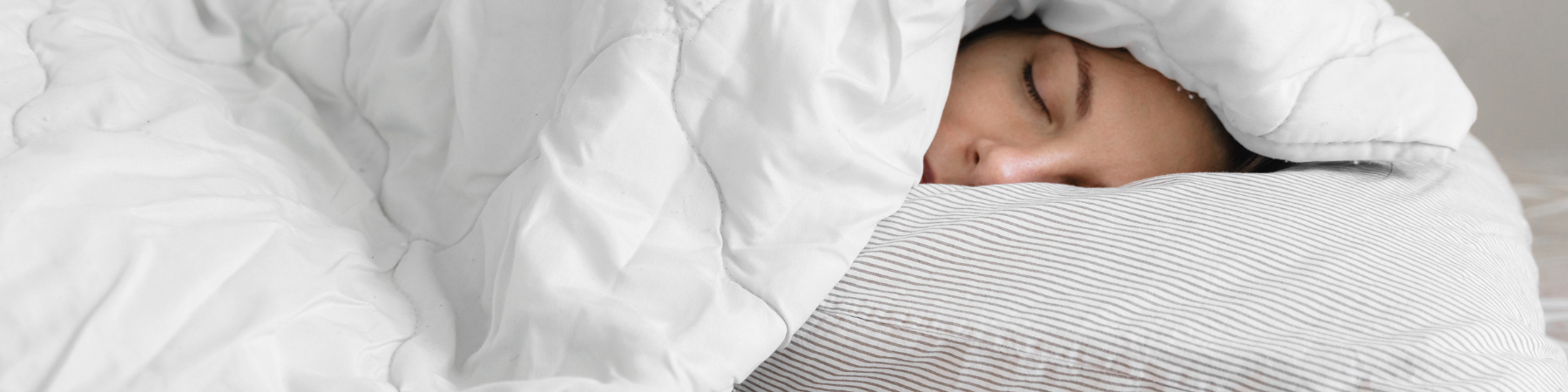 Young woman asleep under blanket