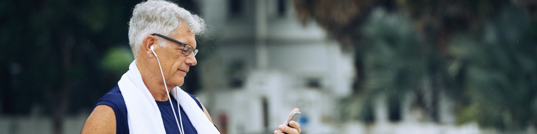 Healthy senior man checking smart phone after exercising outdoors