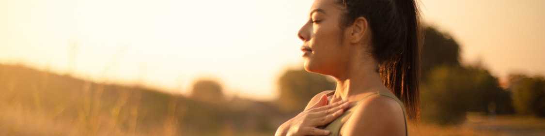 a lady with closed eyes who is focusing on her breathing rate and trying to relax outside