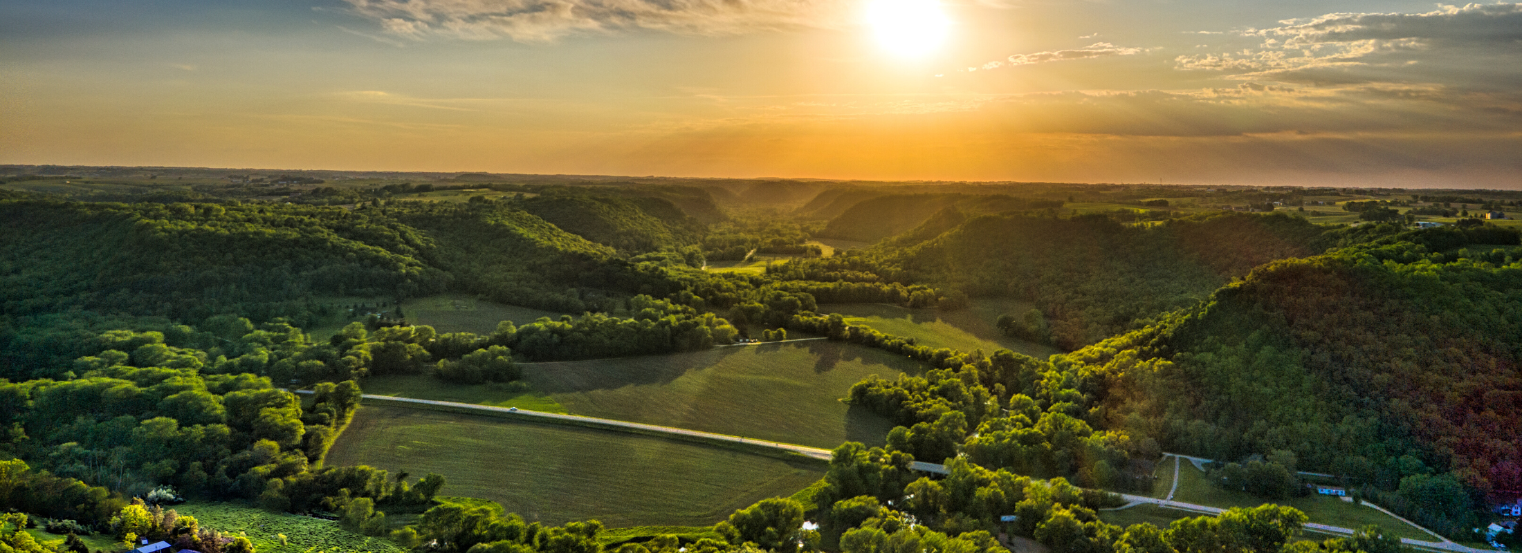 An aerial view of vast green nature and a sunrise